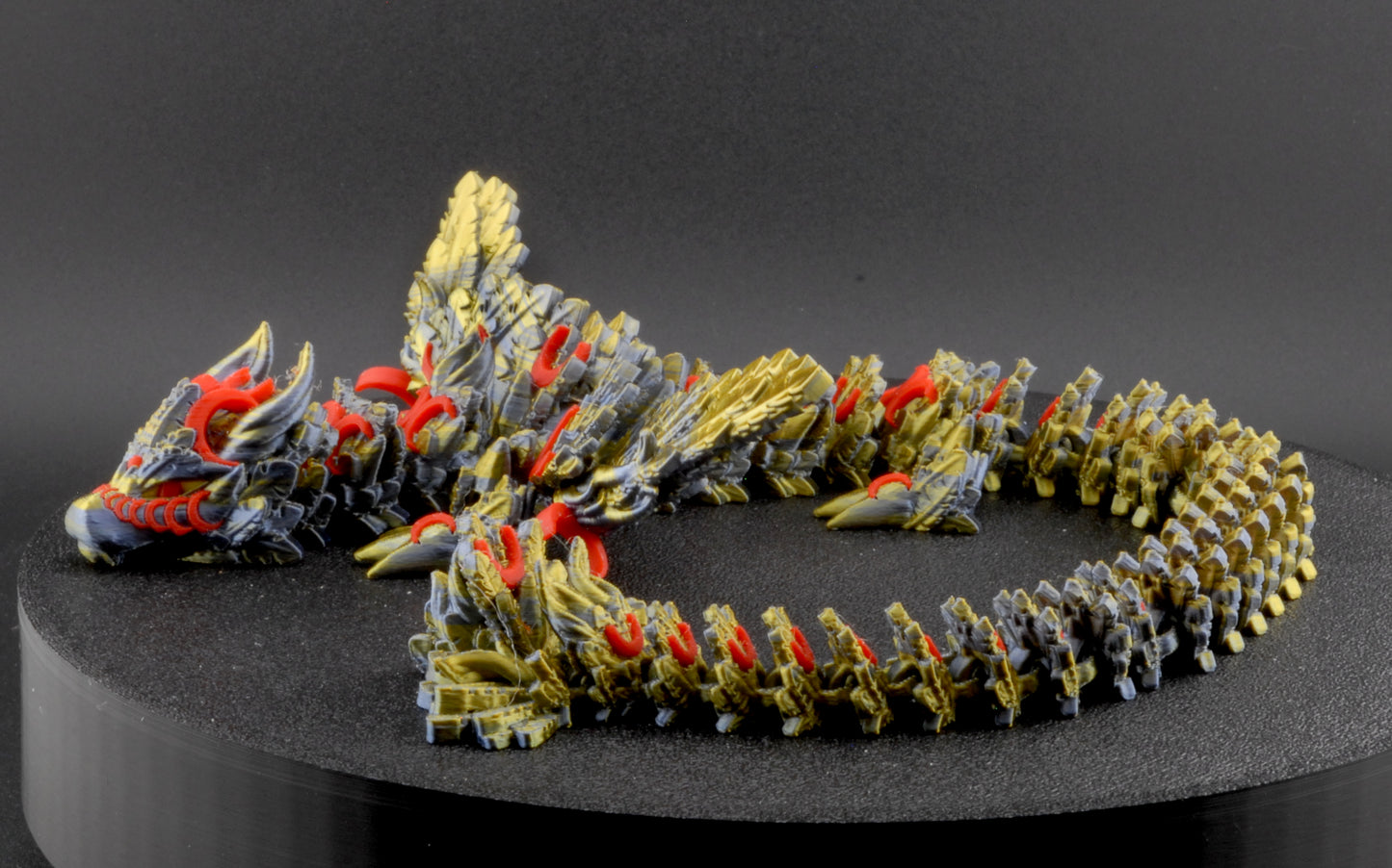 Model of a dragon-like creature on a black stand with a dark background
