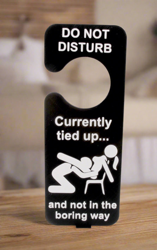 Door sign with humorous message about being tied up, on a white background
