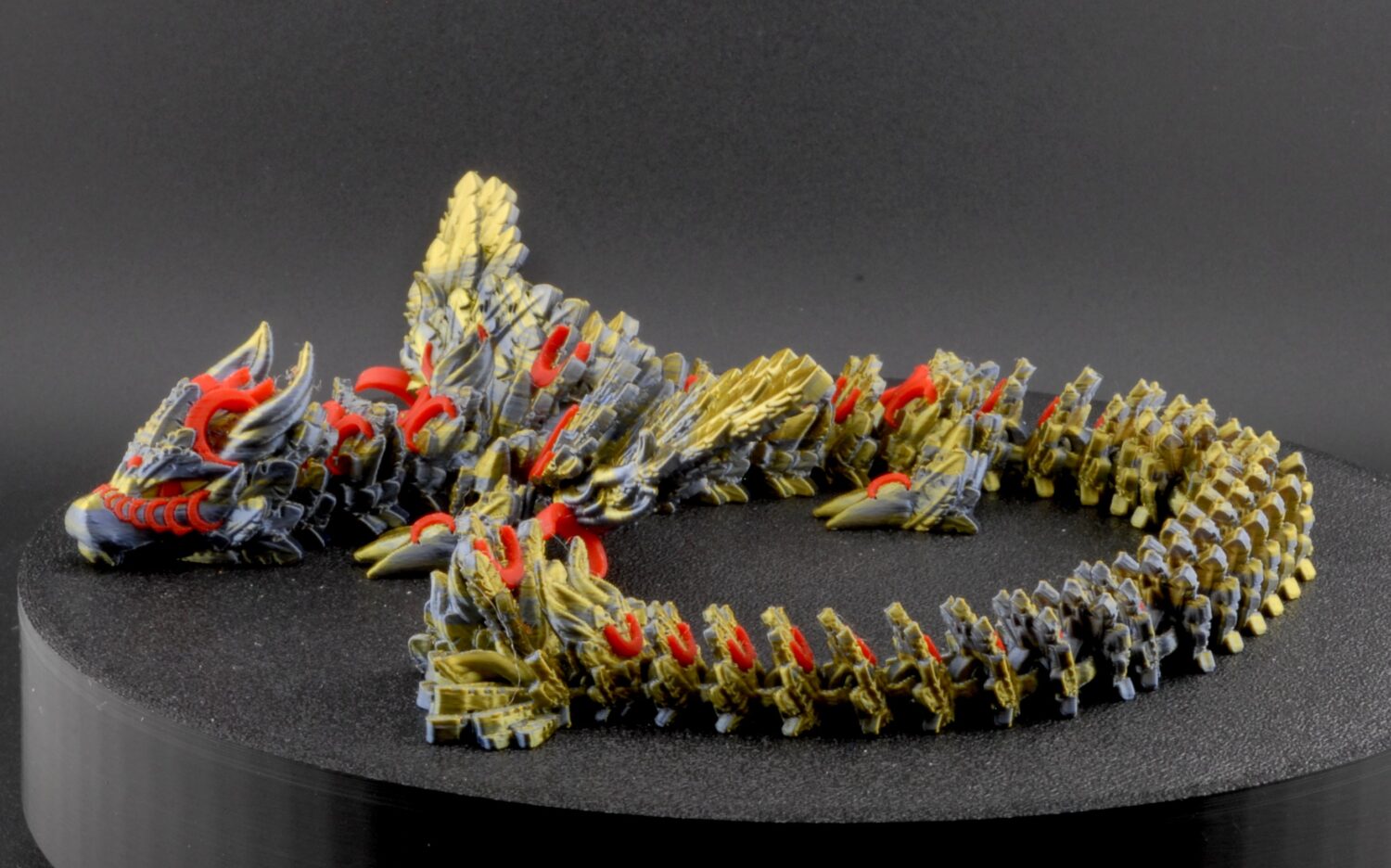 Model of a dragon-like creature on a black stand with a dark background